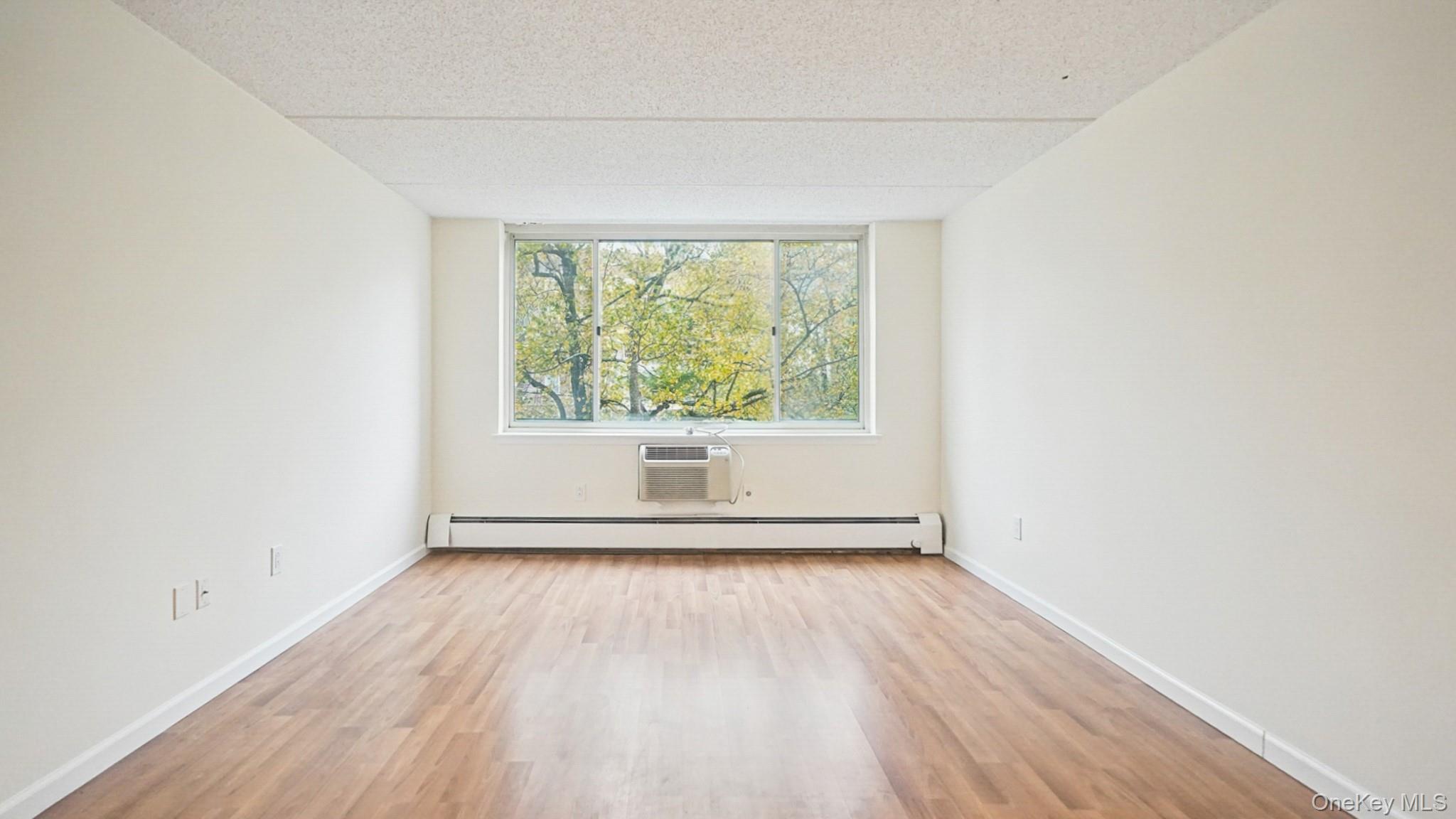 703 Pelham Road, Unit 107 New Rochelle, NY 10805 - Photo 3 of 14 an empty room with wooden floor and windows
