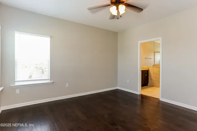 an empty room with wooden floor and a chandelier fan
