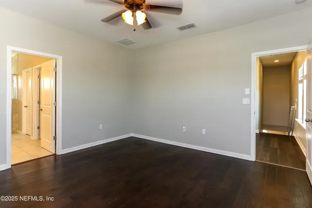 an empty room with a dining space and a chandelier fan