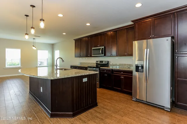 a kitchen with kitchen island granite countertop wooden cabinets a refrigerator and a sink