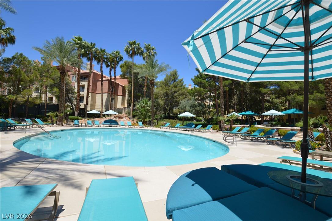 230 East Flamingo Road, Unit 334 Las Vegas, NV 89169 - Photo 30 of 37 Lush palm trees and extensive concrete decking frame a sparkling resort-style swimming pool.