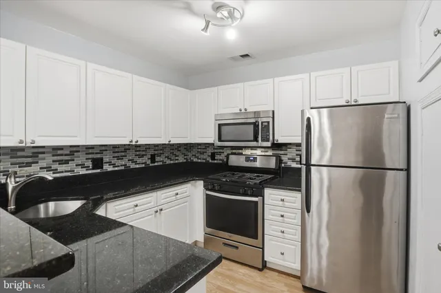 a kitchen with white cabinets and stainless steel appliances