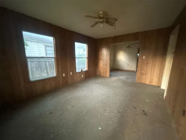 an empty room with windows and fan