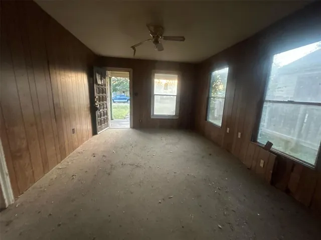 an empty room with windows and chandelier fan