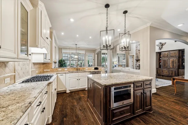 a kitchen with kitchen island granite countertop a sink stove refrigerator and cabinets