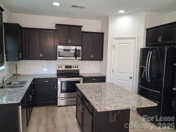 a kitchen with kitchen island granite countertop stainless steel appliances and wooden cabinets