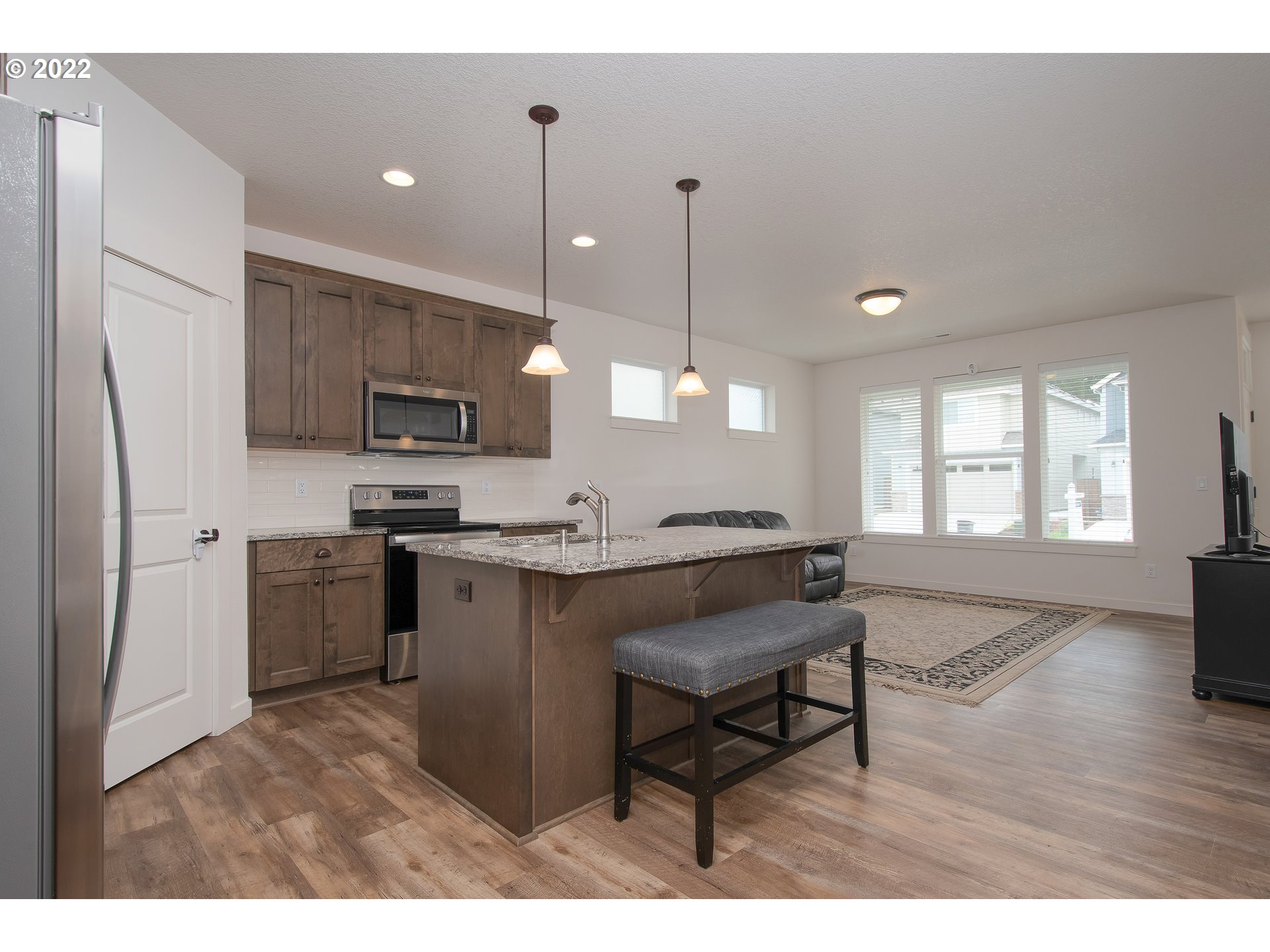 7030 South Ridge Way Ridgefield, WA 98642 - Photo 13 of 27 a open kitchen with stainless steel appliances granite countertop a stove top oven a sink dishwasher a refrigerator and white cabinets with wooden floor