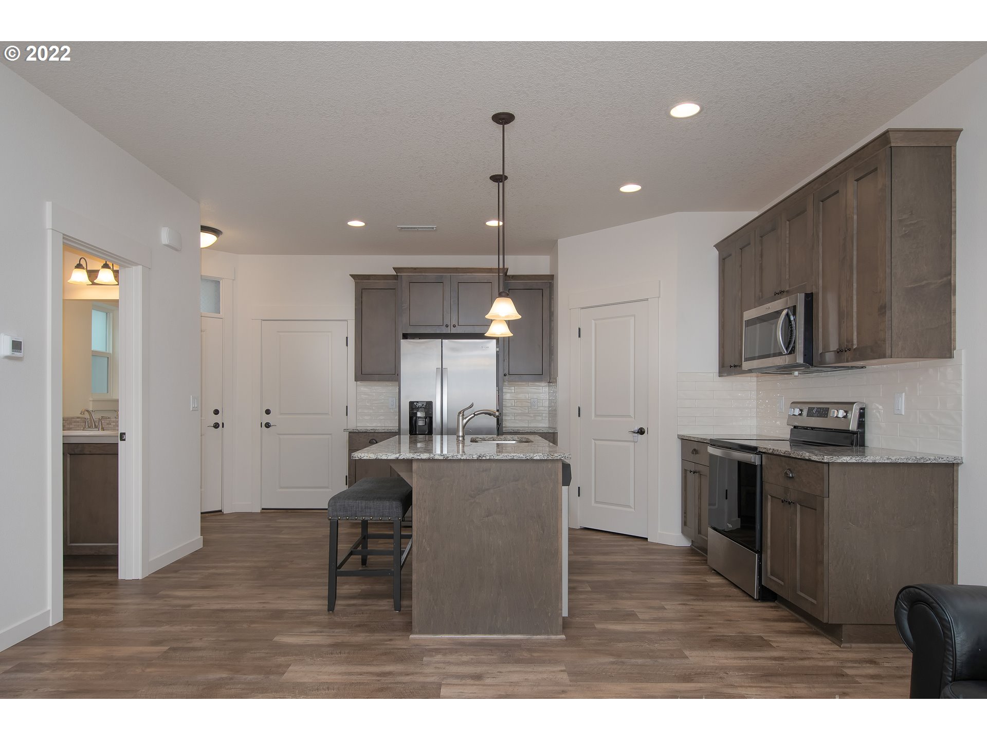 7030 South Ridge Way Ridgefield, WA 98642 - Photo 8 of 27 a kitchen with kitchen island a sink stainless steel appliances and cabinets