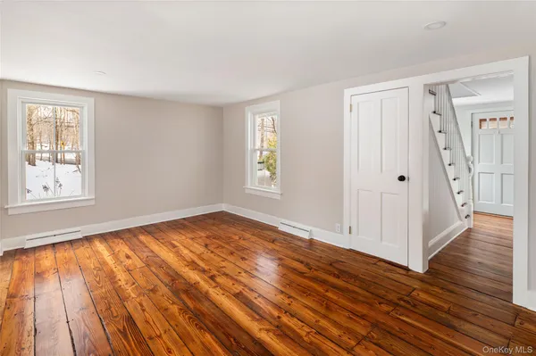 a view of an empty room with wooden floor and windows