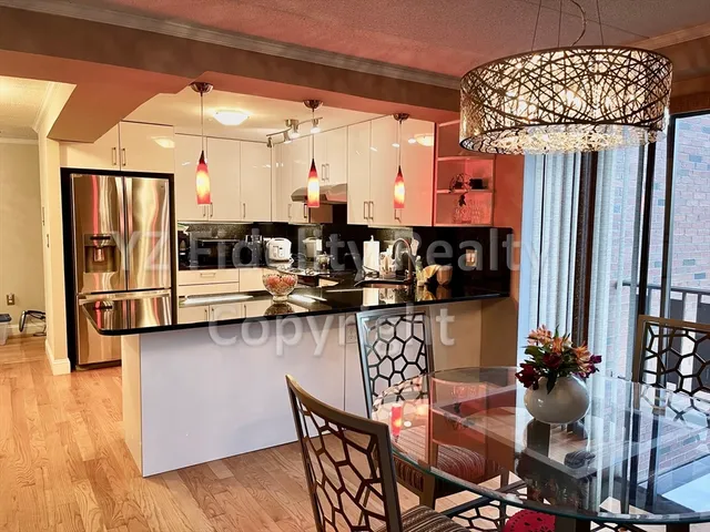 a kitchen with stainless steel appliances kitchen island granite countertop a table chairs and a wooden floor
