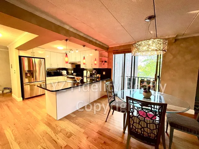 a dining room with stainless steel appliances granite countertop a stove top oven a dining table and chairs with wooden floor