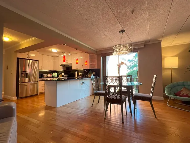 a kitchen with stainless steel appliances granite countertop a stove top oven a sink a dining table and chairs with wooden floor