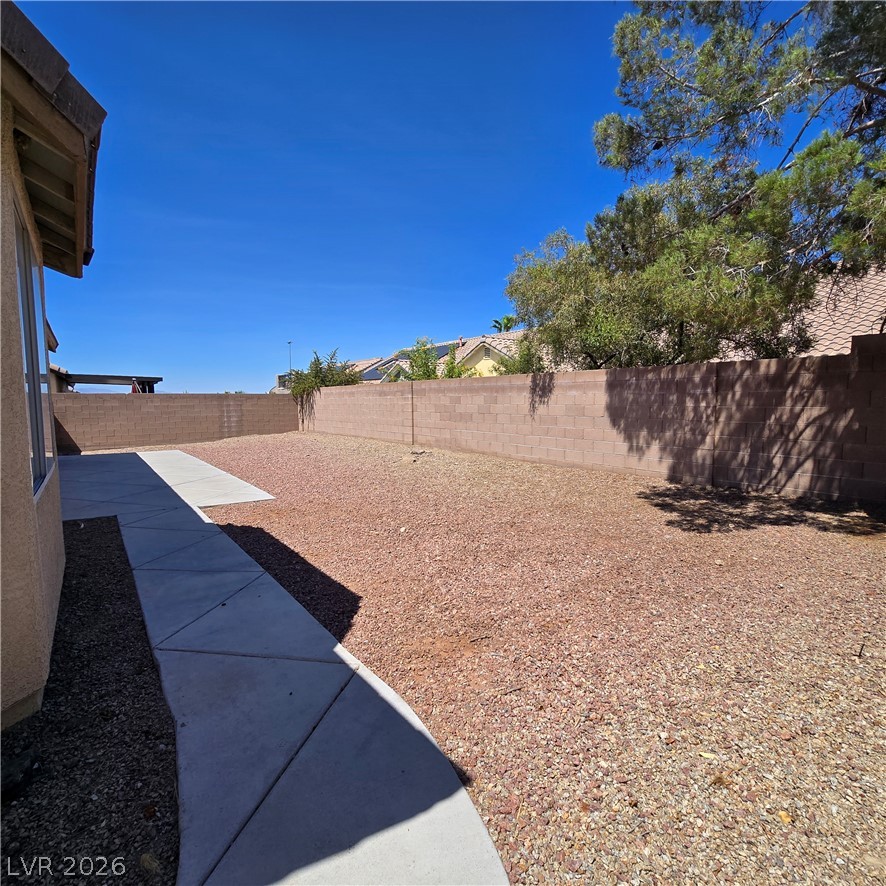 9234 Kingston Road Henderson, NV 89074 - Photo 33 of 38 A spacious backyard with a concrete pathway awaits your landscaping vision.