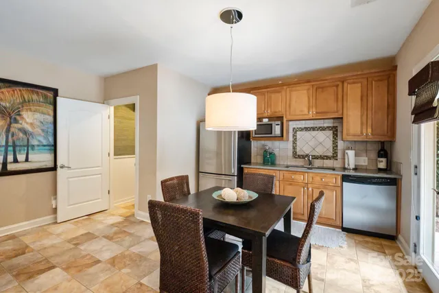 a kitchen with stainless steel appliances granite countertop a stove a refrigerator a kitchen island a dining table and chairs with wooden floor
