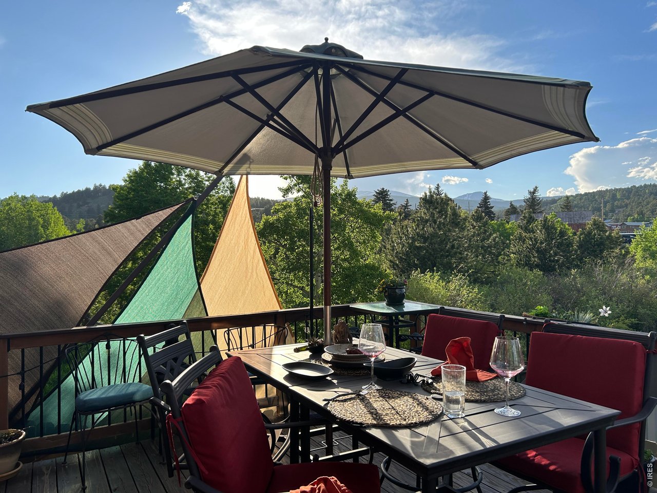 131 West Boulder Street Nederland, CO 80466 - Photo 3 of 46 In-town convenience with extraordinary outdoor dining deck with umbrella, table setting, and mountain views overlooking mature trees.