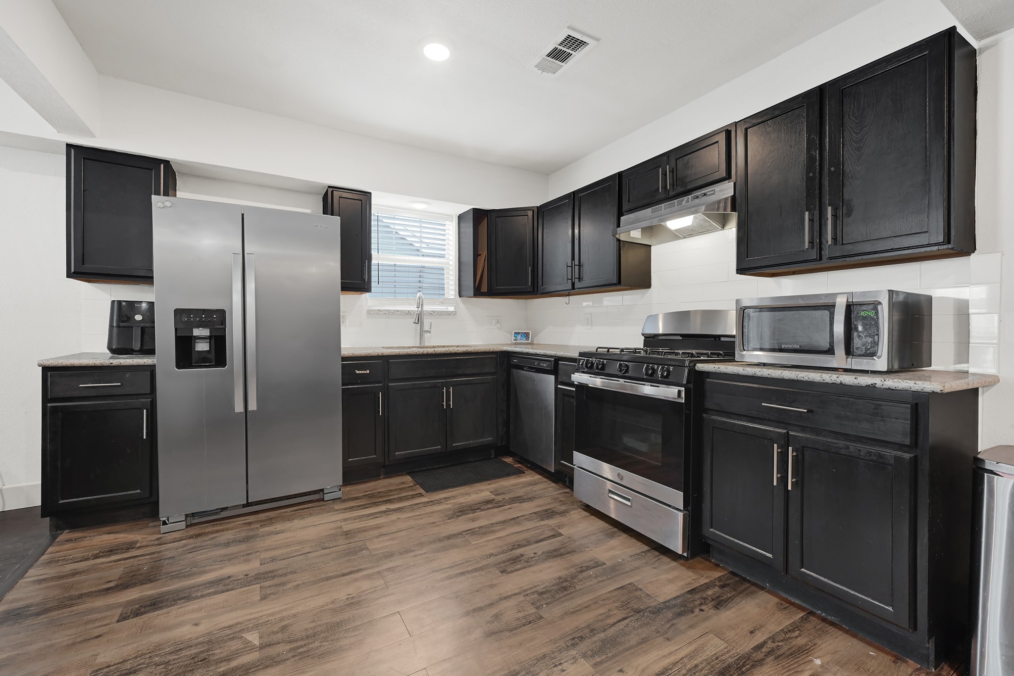 207 Wafer Street Pasadena, TX 77506 - Photo 3 of 26 a kitchen with granite countertop a refrigerator stove and microwave
