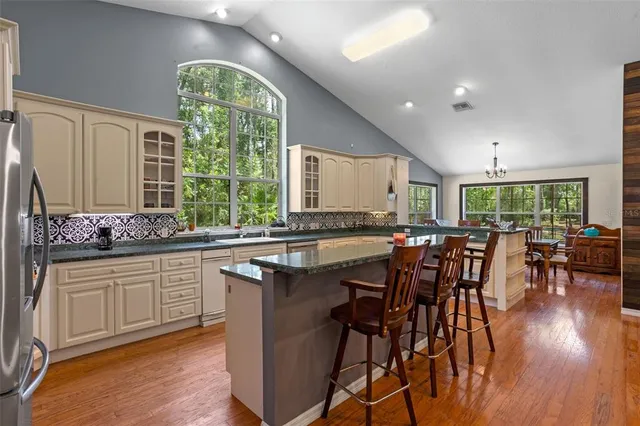 a kitchen with stainless steel appliances granite countertop a kitchen island hardwood floor and a sink