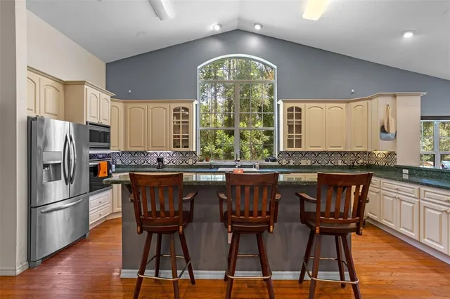 a kitchen with stainless steel appliances a dining table chairs and wooden floor