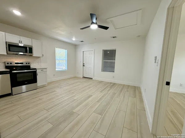 an empty room with wooden floor a ceiling fan and windows