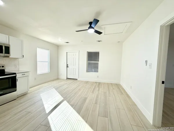 a view of empty room with wooden floor and fan