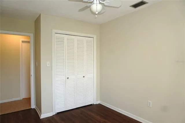 an empty room with wooden floor and fan