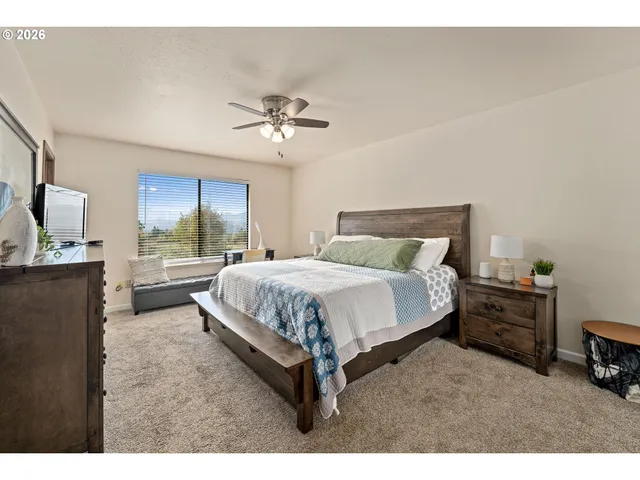 a spacious bedroom with a bed a dresser and a chandelier