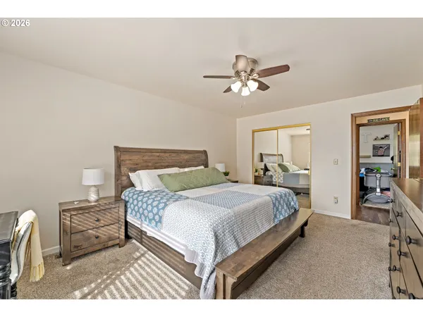 a bedroom with a bed ceiling fan and a wooden floor