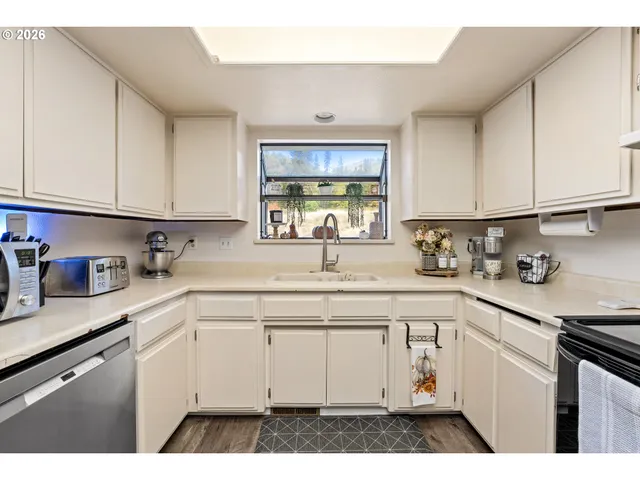 a kitchen with cabinets appliances a sink and a window