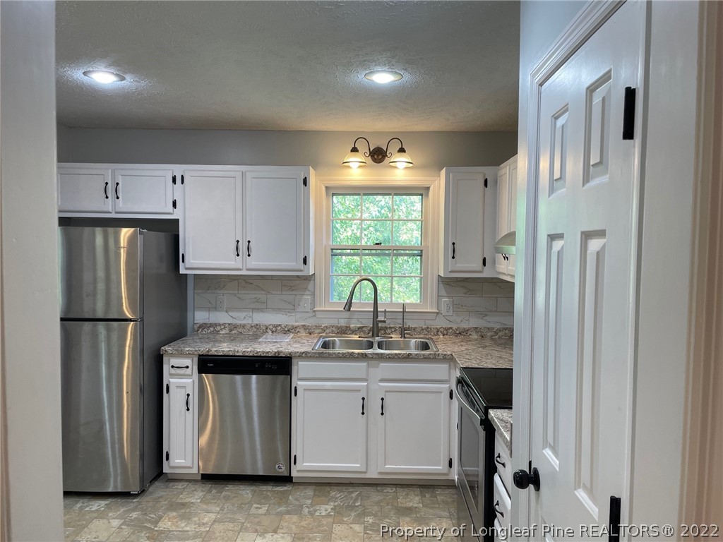 1714 Valley Ridge Drive Fayetteville, NC 28303 - Photo 11 of 32 a kitchen with stainless steel appliances granite countertop a refrigerator sink and white cabinets