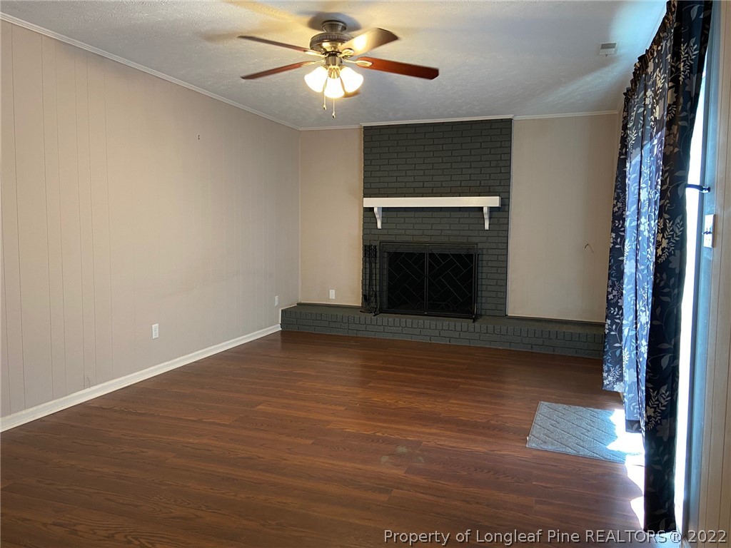 1714 Valley Ridge Drive Fayetteville, NC 28303 - Photo 22 of 32 an empty room with wooden floor fireplace and ceiling fan