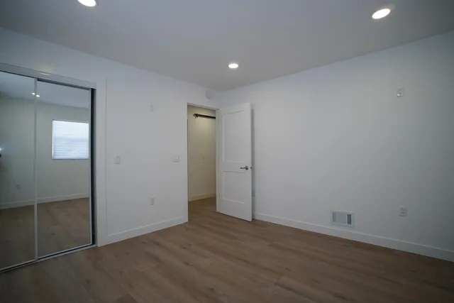 an empty room with wooden floor & closet area