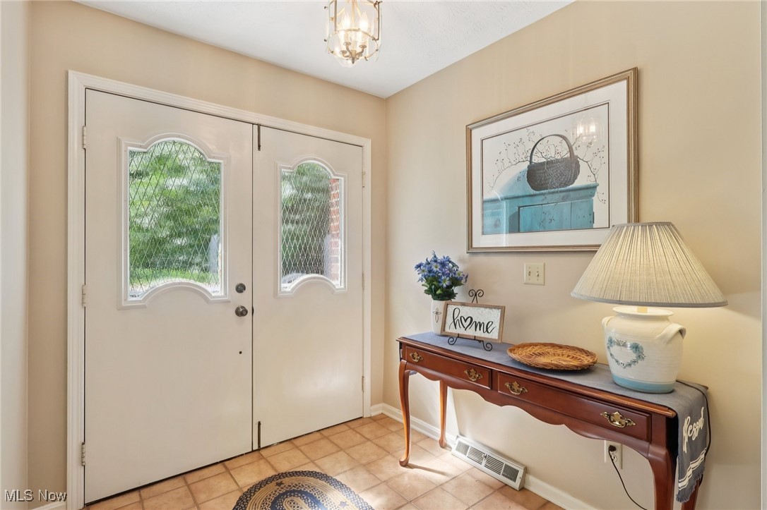 5568 Forest Glen Road Madison, OH 44057 - Photo 5 of 50 Tiled entryway with a chandelier and baseboards