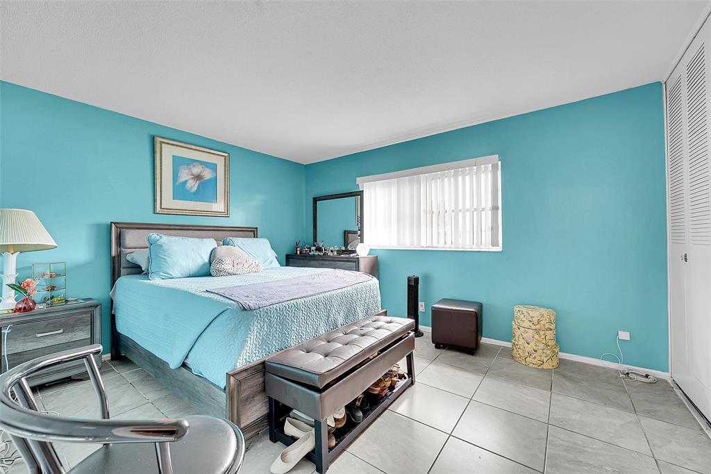 2769 Ashley Drive West, Unit F West Palm Beach, FL 33415 - Photo 9 of 25 a bedroom with a bed and a lamp on desk