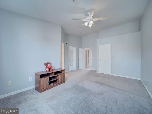 an empty room with chandelier fan and windows