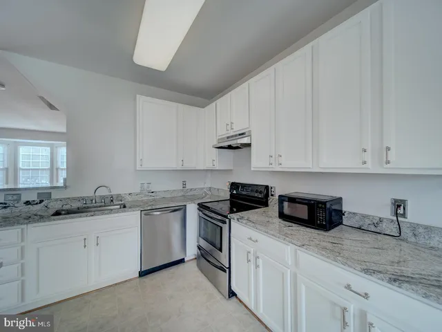 a kitchen with stainless steel appliances granite countertop white cabinets sink and stove