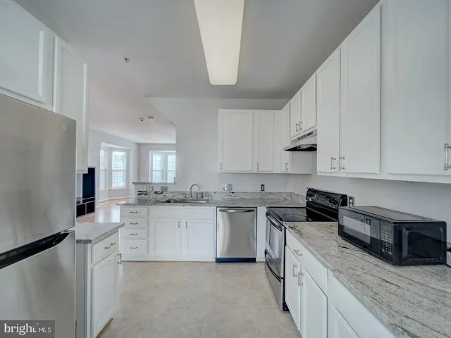 a kitchen with granite countertop a sink a stove top oven and white stainless steel appliances