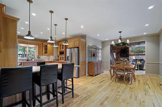 a kitchen with stainless steel appliances granite countertop a stove a sink dishwasher a dining table and chairs with wooden floor