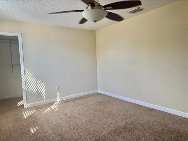 an empty room with windows and fan