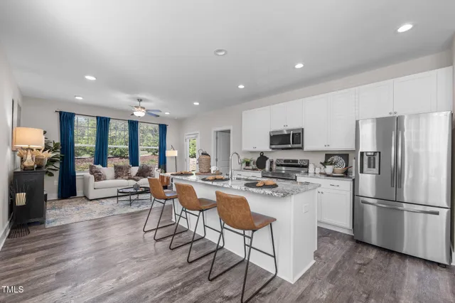a kitchen with stainless steel appliances granite countertop a refrigerator a stove top oven a sink dishwasher and white cabinets with wooden floor