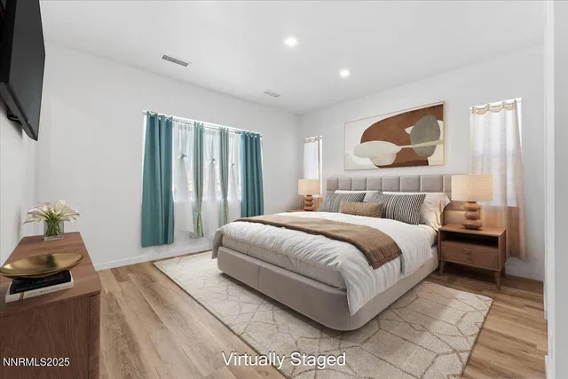 a bedroom with a large bed and a flat tv screen on dresser