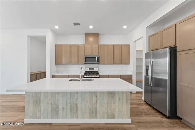 a kitchen with stainless steel appliances granite countertop a refrigerator a stove and a sink