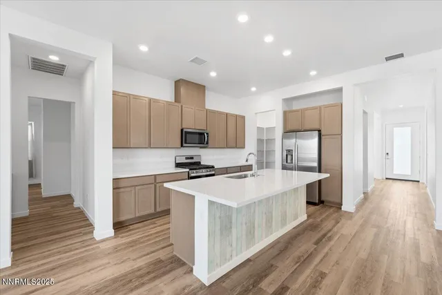 a kitchen with stainless steel appliances a white stove top oven a sink dishwasher and a refrigerator with wooden floor