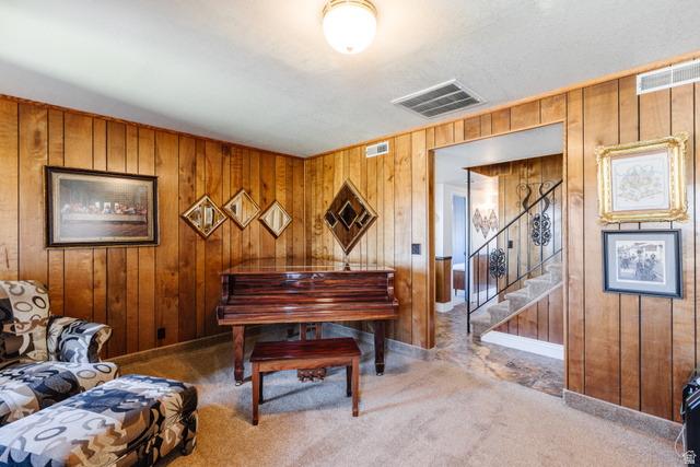 1470 Redwood Tree Street St. George, UT 84790 - Photo 27 of 53 Living area featuring wood paneling walls, neutral carpet flooring, and a cased opening leading to a staircase with wrought iron railing