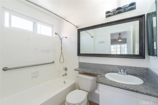 a bathroom with a granite countertop sink toilet a mirror and shower