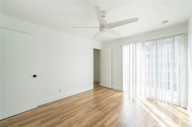 an empty room with wooden floor fan and windows