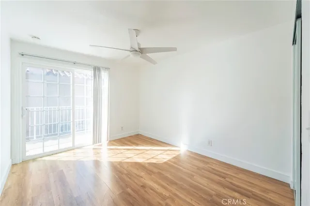 an empty room with wooden floor cabinet and windows