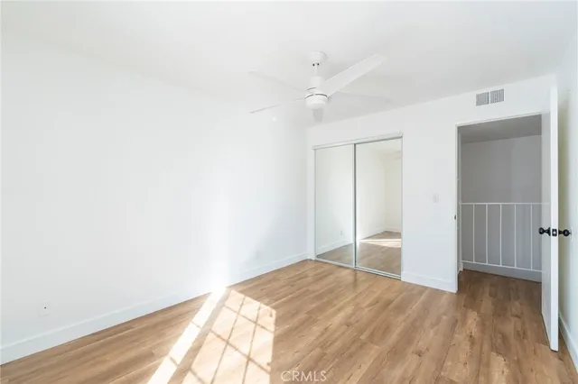 a view of empty room with wooden floor and fan