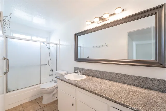 a bathroom with a granite countertop sink mirror vanity and toilet