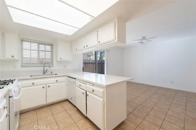 a kitchen with white cabinets a sink dishwasher and a stove with wooden floor