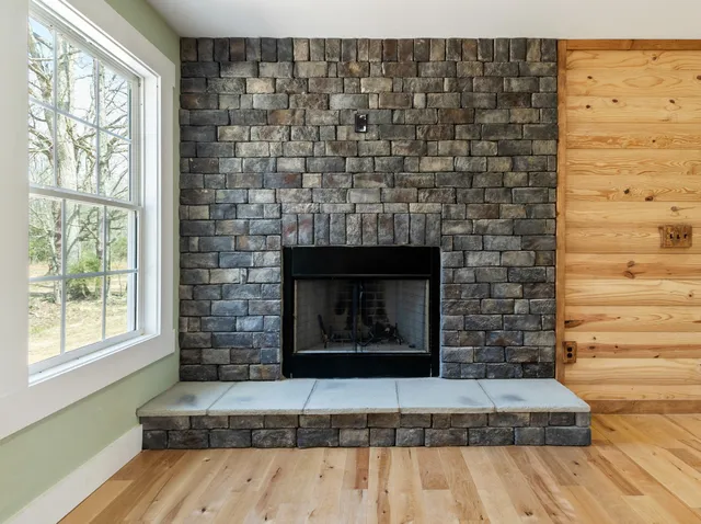 a bedroom with a bed next to a window with wooden floor